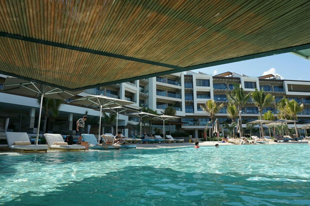 a pool with people in it by a building with a roof