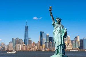 La statue de la Liberté surplombe le paysage urbain de New York, au bord du fleuve, dans le sud de Manhattan. Architecture et bâtiments conçus dans une optique touristique.