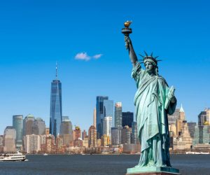 La statue de la Liberté surplombe le paysage urbain de New York, au bord du fleuve, dans le sud de Manhattan. Architecture et bâtiments conçus dans une optique touristique.