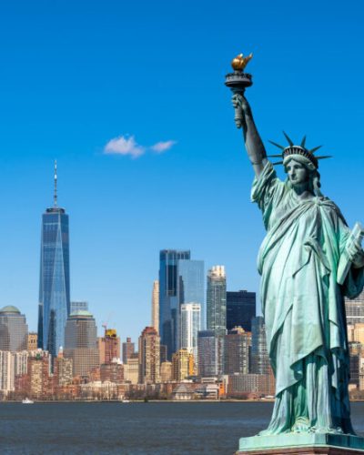 La statue de la Liberté surplombe le paysage urbain de New York, au bord du fleuve, dans le sud de Manhattan. Architecture et bâtiments conçus dans une optique touristique.