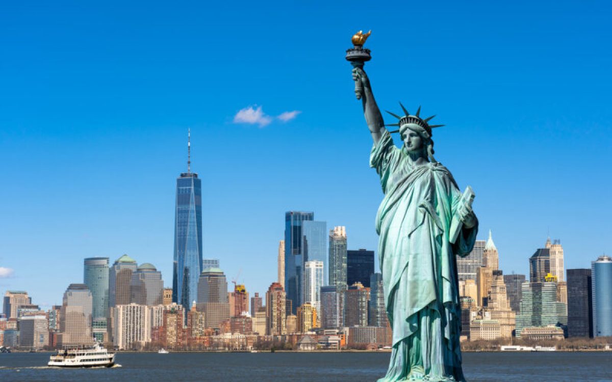 La statue de la Liberté surplombe le paysage urbain de New York, au bord du fleuve, dans le sud de Manhattan. Architecture et bâtiments conçus dans une optique touristique.