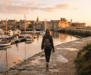 Promeneuse face au port fortifié de Saint-Malo au coucher du soleil